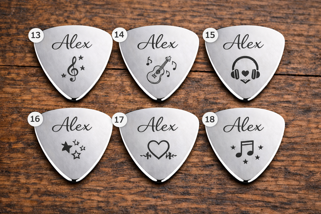 Set of eight silver guitar picks with engraved designs on a wooden surface