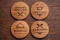 Four wooden coasters with engraved text and symbols on a wooden surface
