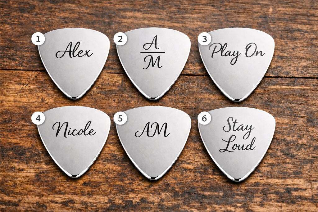 Six silver guitar picks with engraved names on a wooden surface