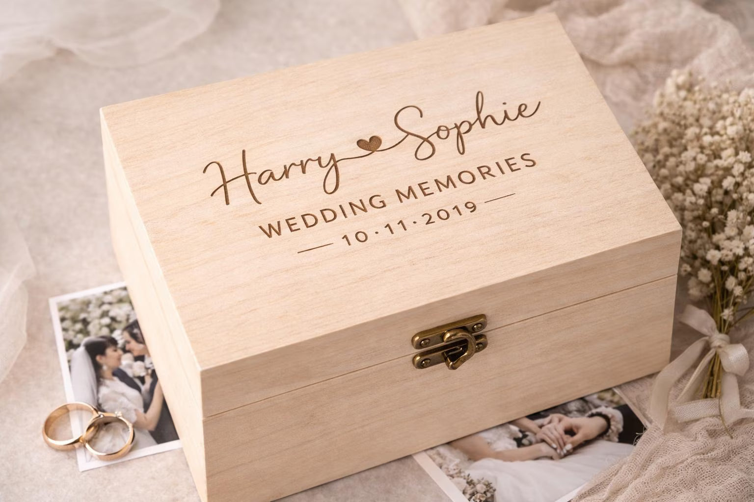 Wooden box engraved with 'Harry & Sophie Wedding Memories 10.11.2019' surrounded by wedding photos and rings.