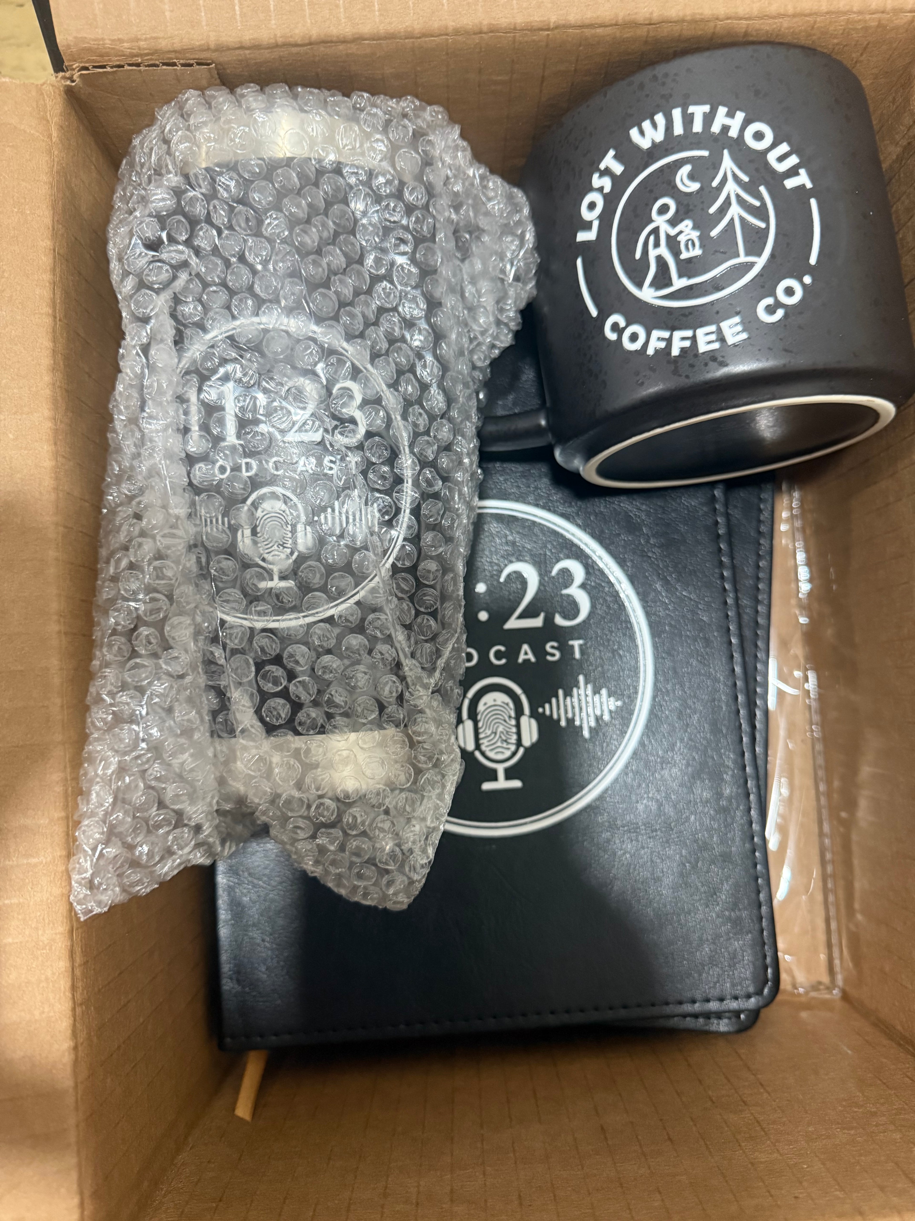 UV DTF custom items. Notebooks, mugs and Tumblers. Packaged items including a mug, a phone case, and a phone in a cardboard box.
