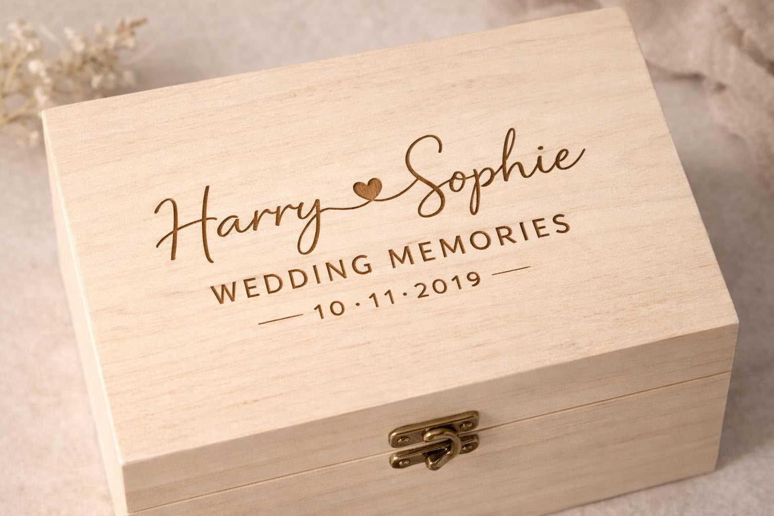 Wooden box engraved with 'Harry & Sophie Wedding Memories 10.11.2019' on a neutral background